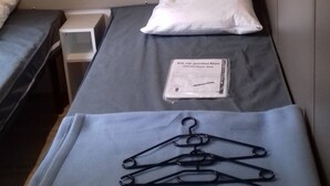 Ein Einzelbett mit einem weißen Kopfkissen und einer kleinen weißen Schachtel darauf.