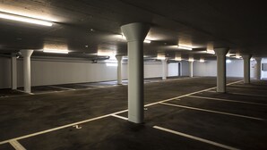 A parking garage with concrete pillars and marked parking spaces. - Spengler Hostel (Davos)