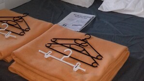 Ein Hotelzimmer mit Bett, Kissen, Nachttisch, Lampe und Fenster.