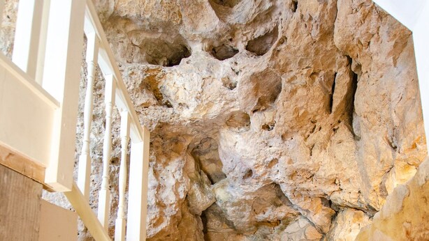 Una escalera con paredes de piedra y barandilla blanca.