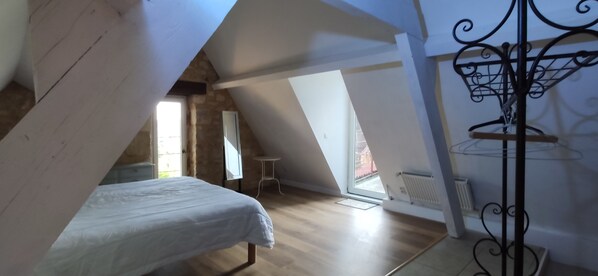 A bedroom with a sloped ceiling, a bed, a radiator, and a window. - Unusual gîte, Le Troglodyte with panoramic view (Domme)