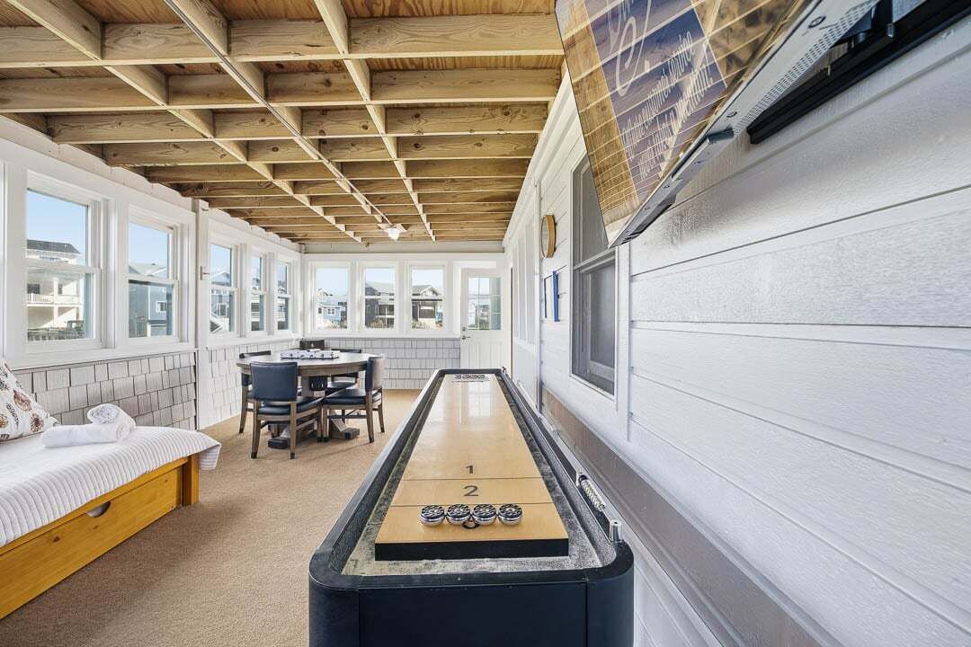 A cozy room with a shuffleboard table, a bed, a dining table, and a view of the outside.