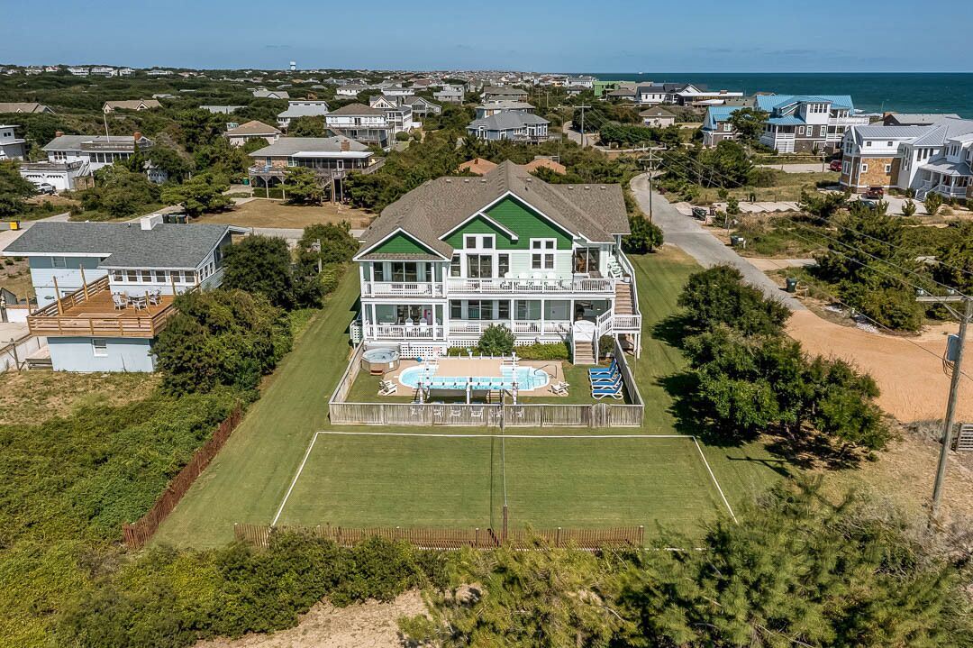 A large two-story house with a pool and a tennis court in the backyard.