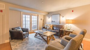 A living room with a sofa, armchairs, a coffee table, and a lamp.