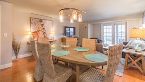 A dining area with a wooden table, wicker chairs, and a modern chandelier.