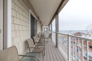 Relax on the covered balcony with comfortable seating and dining areas, taking in the views of the pier and Ferris wheel in the distance.