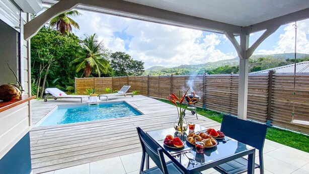 Un giardino con piscina, un barbecue e un tavolo da pranzo con cibo.
