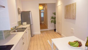 A modern kitchen with white cabinets, a stainless steel sink, and a dining area with a white table. - Stunning townhouse at Plymouth Hoe (Plymouth)