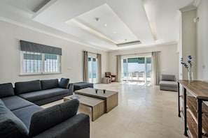 A modern living room with a sectional sofa, a coffee table, and a wooden dining table.