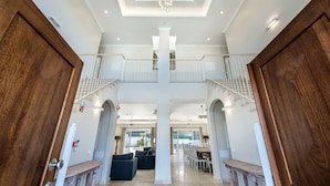 A spacious foyer with a high ceiling, a chandelier, and a staircase leading to an upper level.
