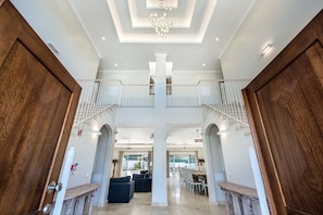 A spacious foyer with a high ceiling, a chandelier, and a staircase leading to an upper level.