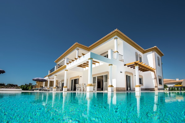 A large, two-story house with a swimming pool in front.