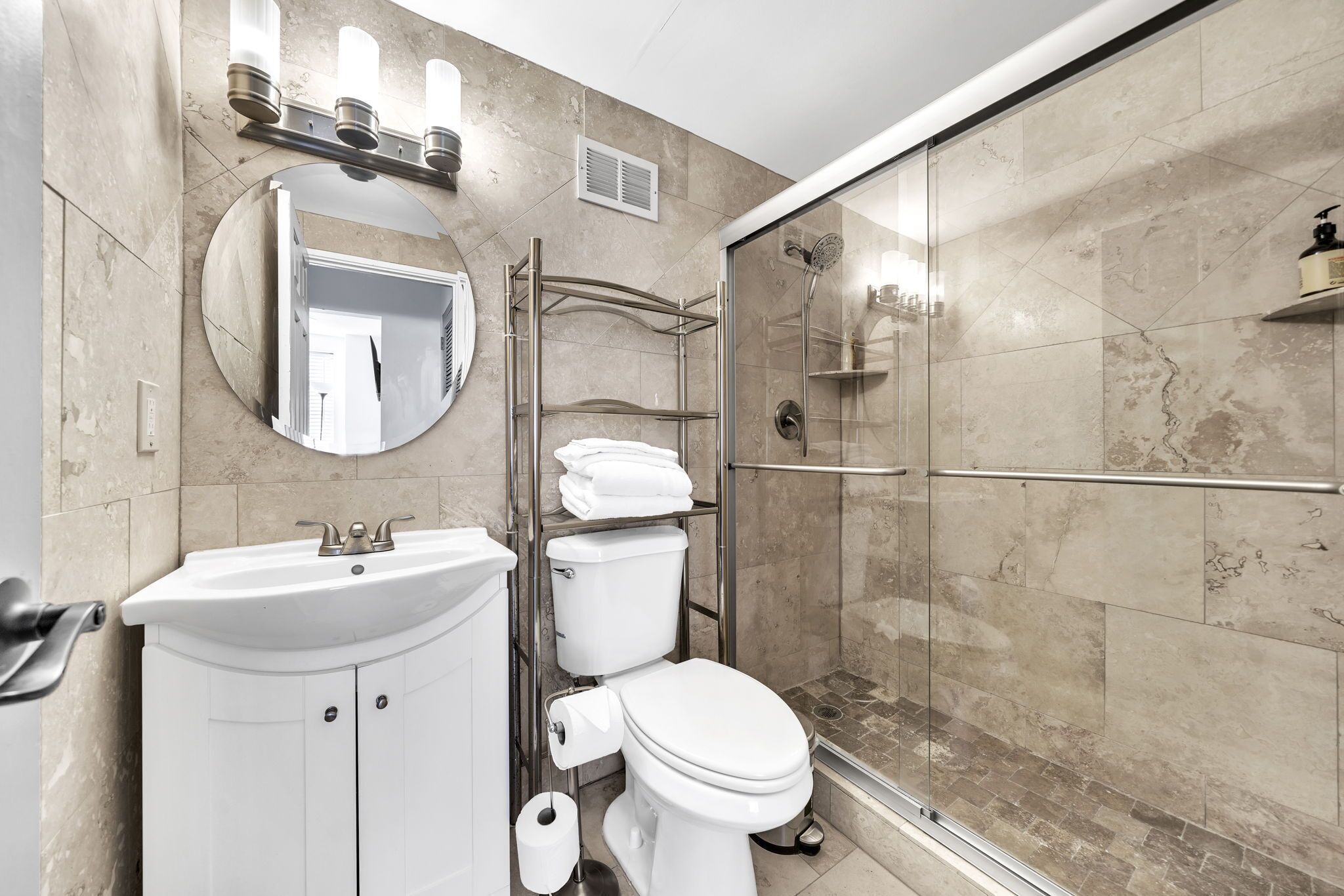 A modern bathroom with a sink, toilet, and glass-enclosed shower.