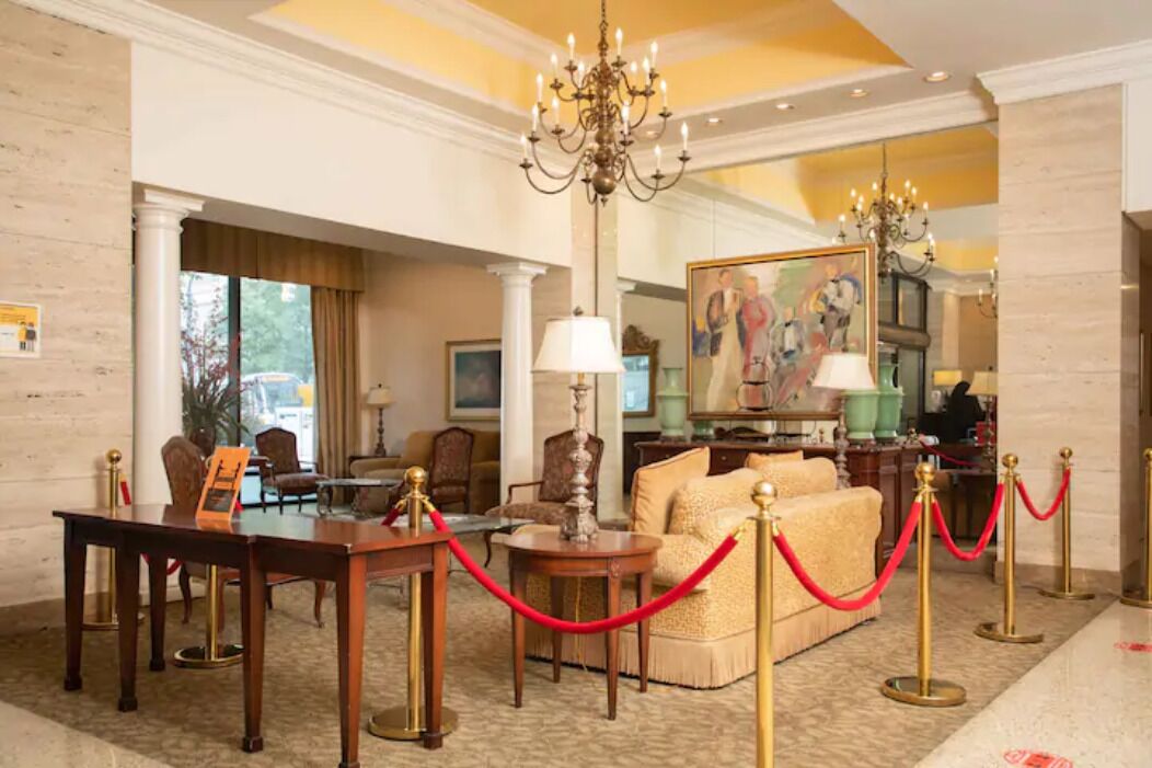 A hotel lobby with a chandelier, a sofa, a table, and a painting on the wall.
