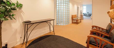 Un intérieur moderne avec un plancher en bois, un tapis noir, une chaise en bois, une table et une plante.