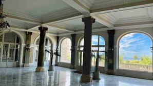 A spacious lobby with marble floors, large arched windows, and classical columns.