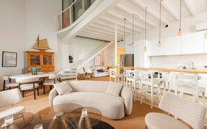 Ein modernes Interieur mit einer gebogenen Couch, Essbereich, Küche und einer Treppe.