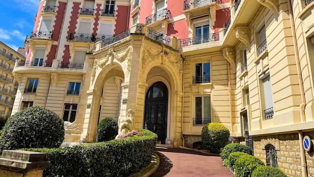 A multi-story building with ornate balconies and a central entrance.