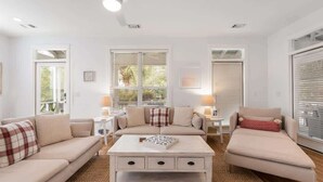 A modern living room with a beige sofa, a white coffee table, and a small side table with a lamp. - Summer Secret- Heated Pool- 4 Bikes- Prime Beach (Santa Rosa Beach)