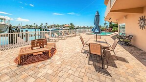 Een terras met buitenmeubilair, een zwembad en uitzicht op de jachthaven.