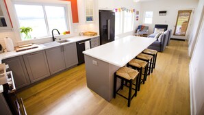Una cocina moderna con una isla grande, piso de madera y vistas al exterior.