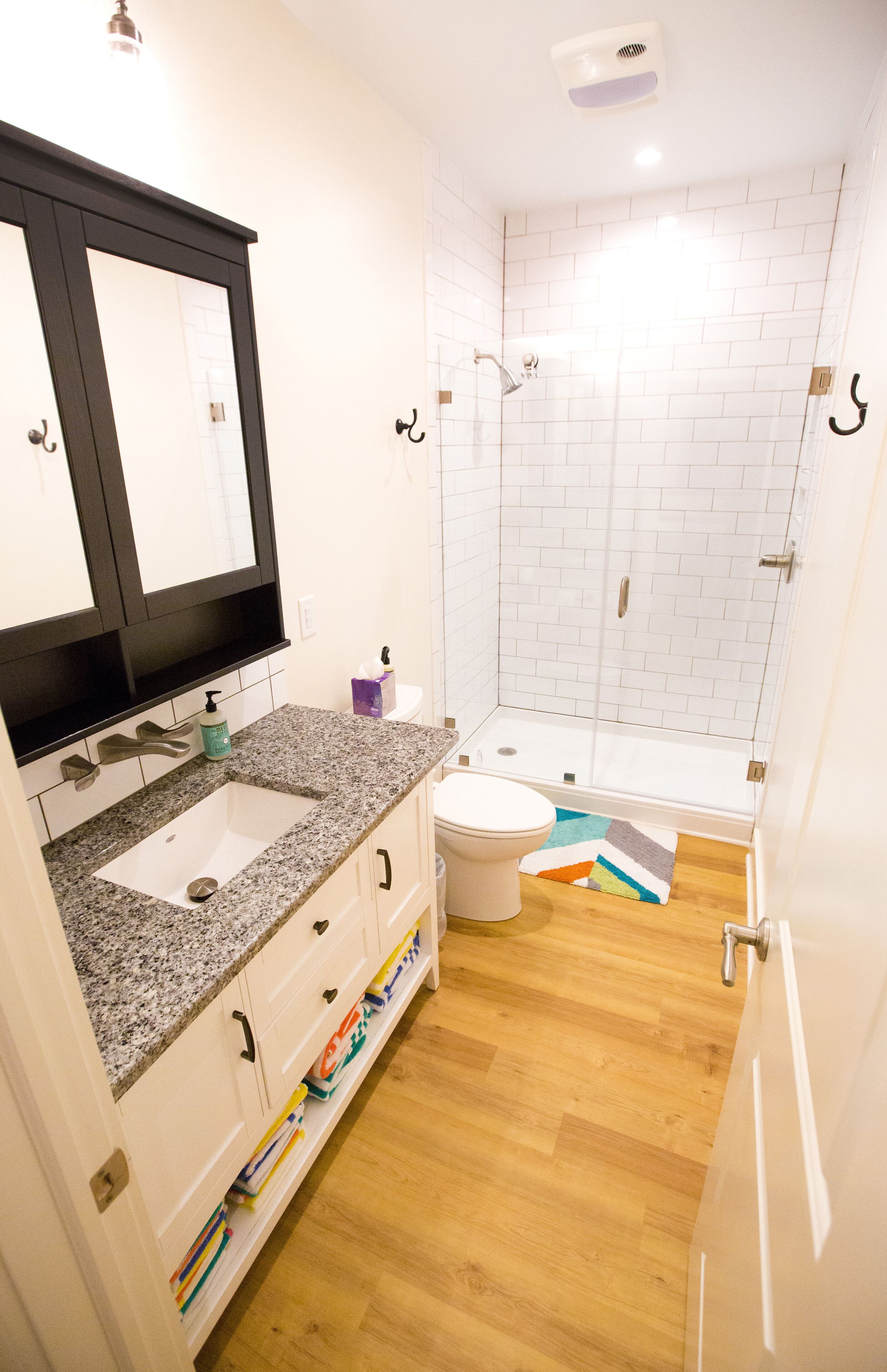 A bathroom with a double sink, a toilet, a shower, and a mirror.