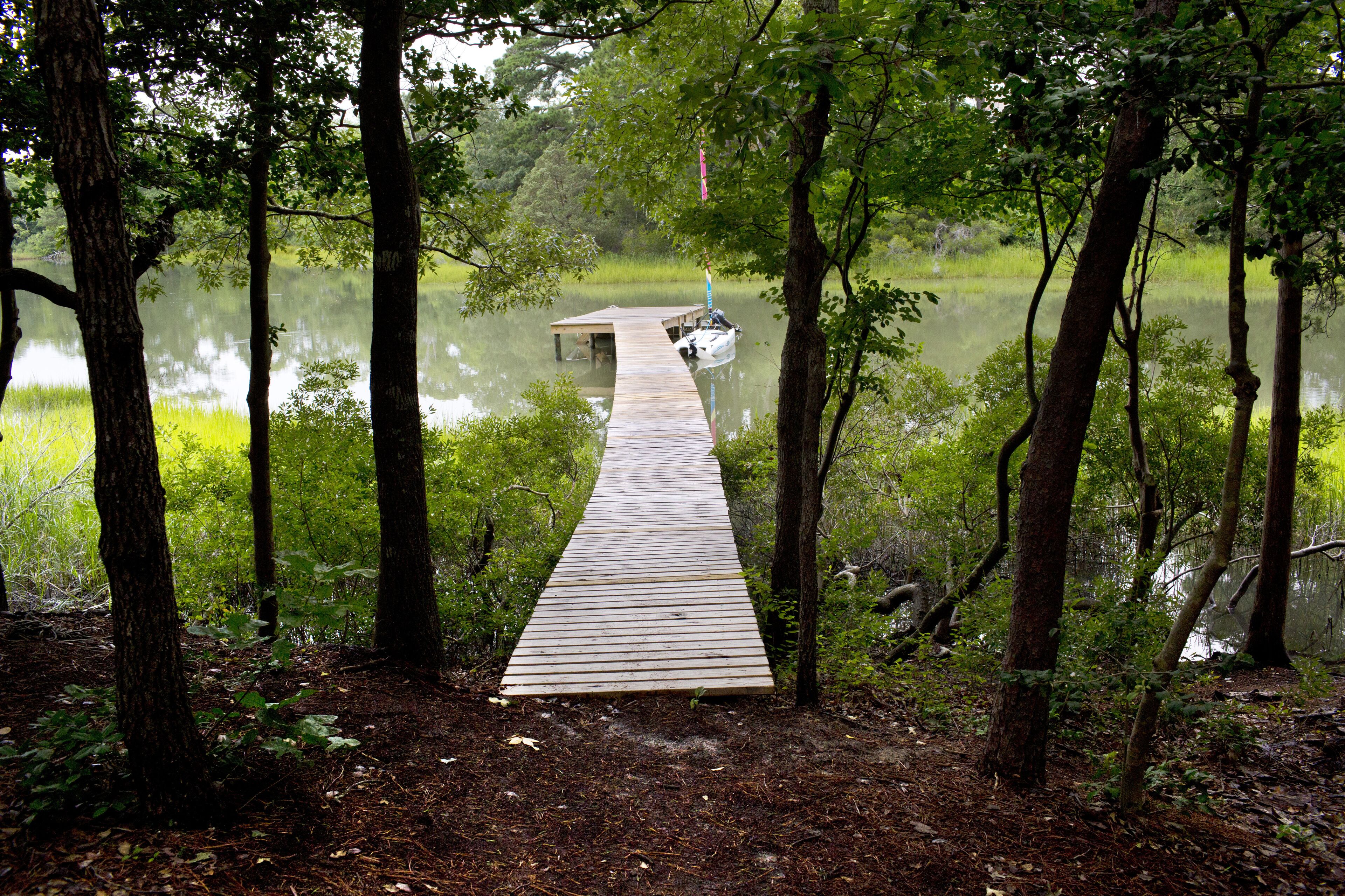 A wooden dock extending into a calm lake surrounded by dense forest.
