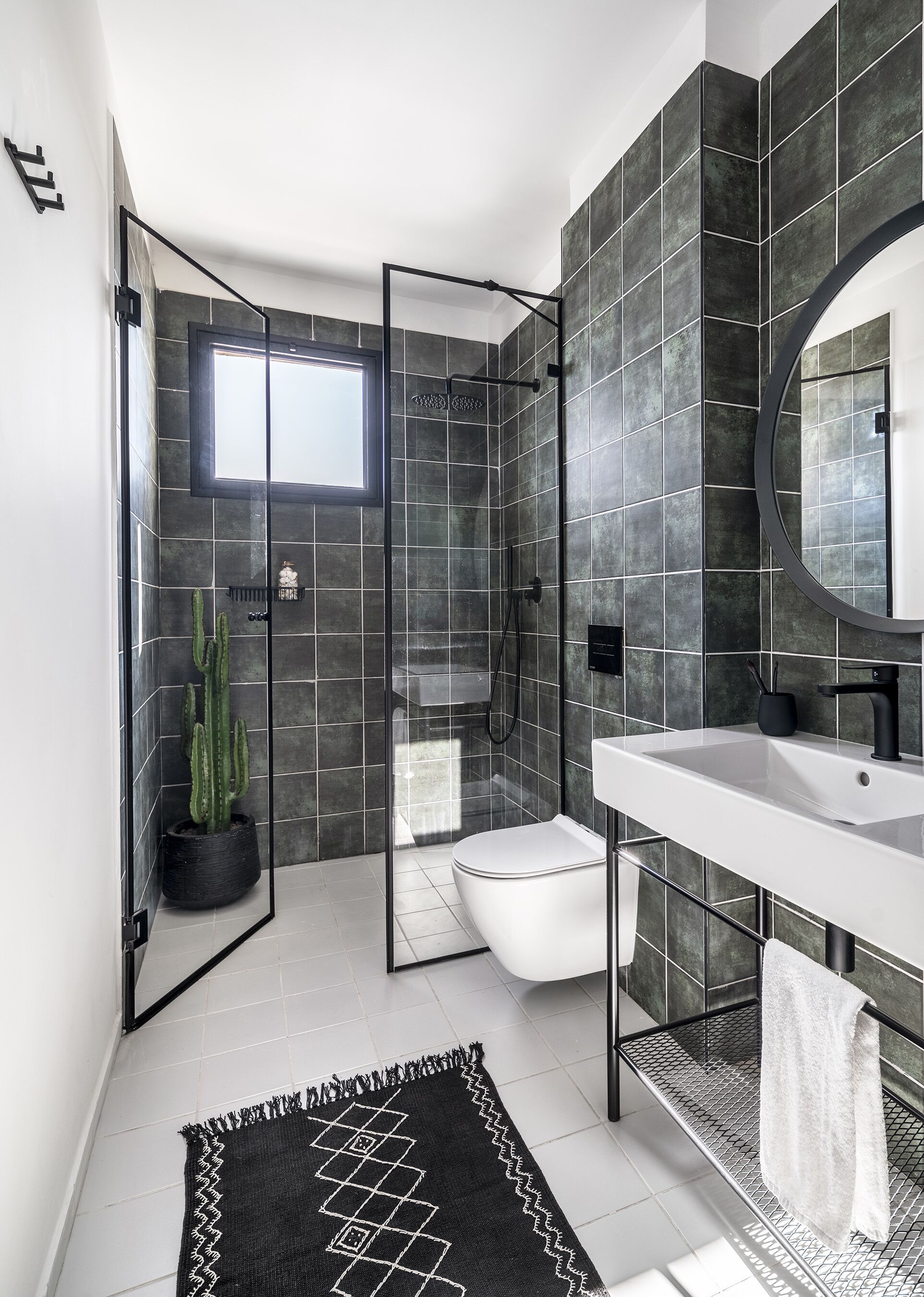 A modern bathroom with a glass-enclosed shower, a white toilet, a sink with a black faucet, and a large mirror.