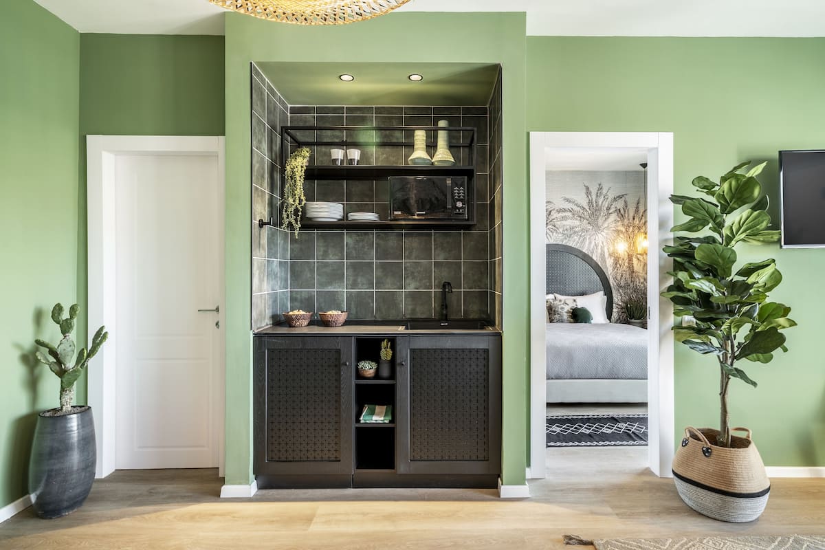 Une cuisine moderne avec des meubles de couleur sombre, un four à micro-ondes encastré et un petit îlot central doté d’un évier.