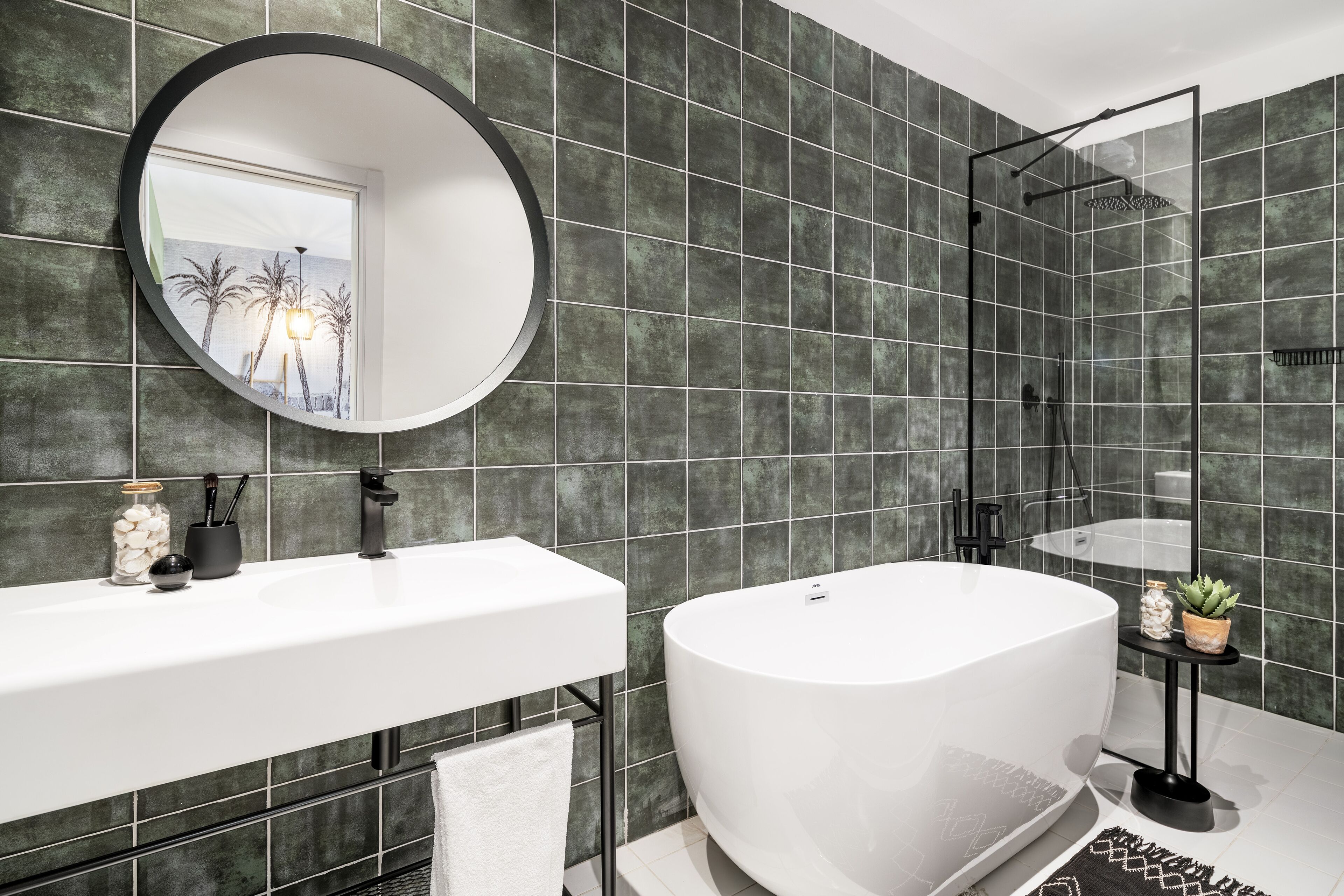 Un baño moderno con una bañera grande, un espejo redondo y una zona de ducha.