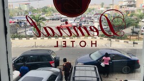 A view of a busy street with cars and a hotel sign in the foreground. - Demiral Hotel Ikeja (Lagos)