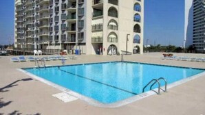 A swimming pool with a clear blue water surface, surrounded by lounge chairs and a concrete deck. - Sweeping ocean and bayviews, large outdoor pool,2 Br/2 Ba. (Ocean City)
