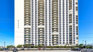 A tall, multi-story hotel with a uniform facade, numerous balconies, and a clear sky. - Sweeping ocean and bayviews, large outdoor pool,2 Br/2 Ba. (Ocean City)
