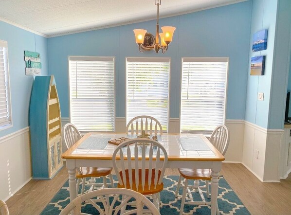 Cozy dining area with a table for four, surrounded by classic chairs and a chandelier.