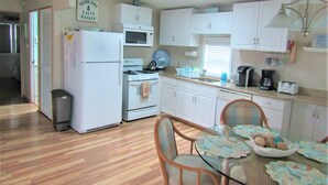A compact kitchen with a refrigerator, stove, microwave, and a dining area with a table and chairs.