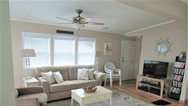 A living room with a beige sofa, a white coffee table, a television on a wooden stand, and a bookshelf filled with books.