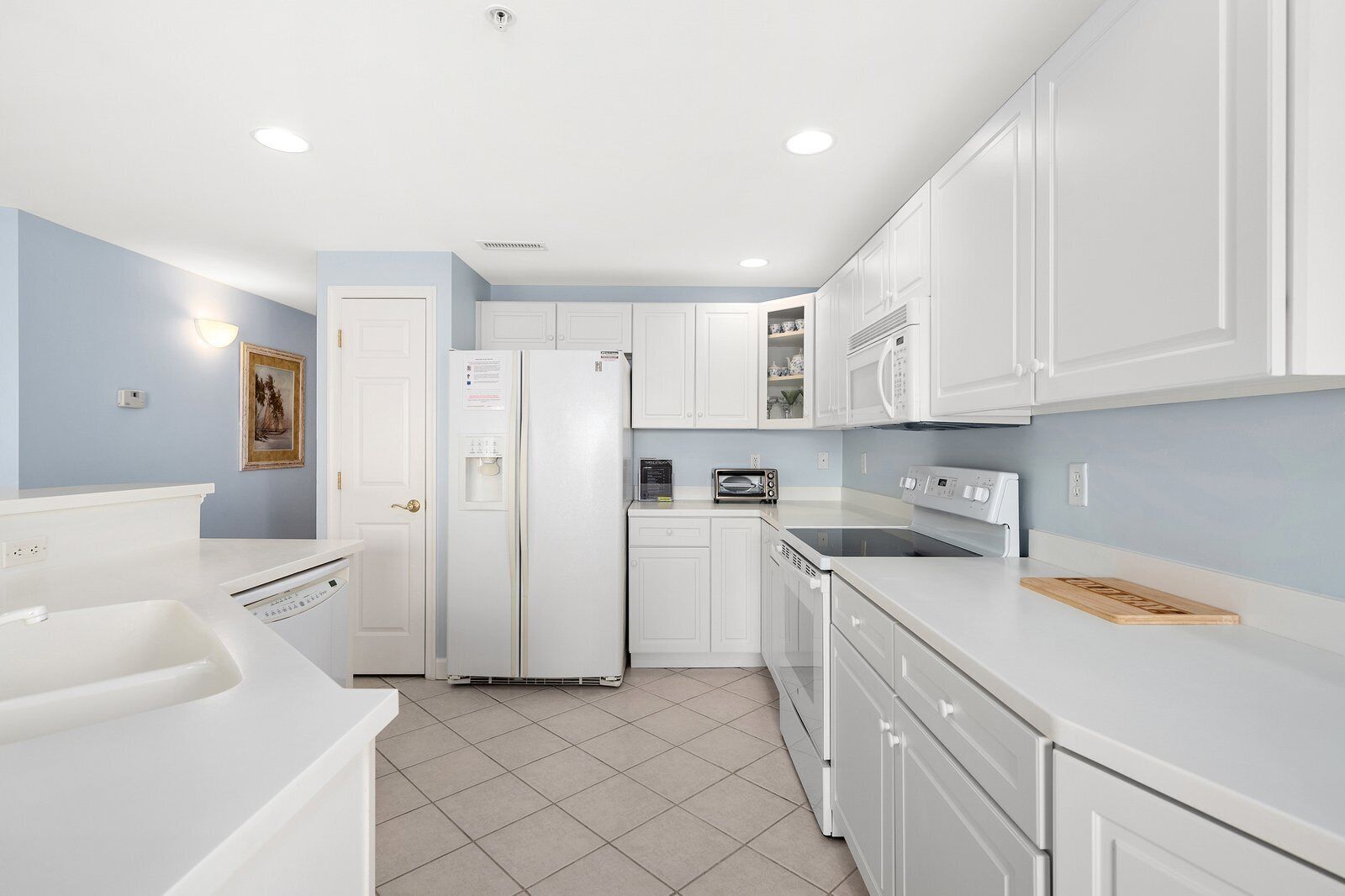 A modern kitchen with white cabinetry, a built-in dishwasher, a refrigerator, a microwave, and a toaster.