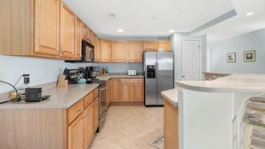 A kitchen with wooden cabinets, stainless steel appliances, and a countertop with a coffee maker and toaster. - Beautiful, with a great floor plan, in down town OC, walk to beach &boards, has an outdoor pool. (Ocean City)