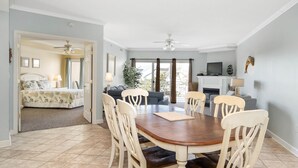 A dining area with a wooden table and six chairs, a sofa, a TV, and a fireplace. - Beautiful, with a great floor plan, in down town OC, walk to beach &boards, has an outdoor pool. (Ocean City)
