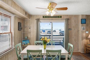 Enjoy meals and conversations around the table in this cozy space with a ceiling fan above and a view of the street outside.