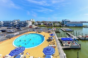 Relax by the pool surrounded by lounge chairs and umbrellas, with a dock and boats nearby.