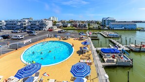 Ein Poolbereich mit Holzterrasse, Liegestühlen und Sonnenschirmen.