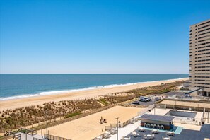 A beach view from a hotel with a pool and outdoor seating.