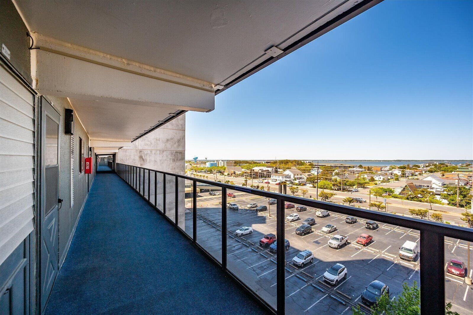 A balcony with a view of a parking lot and buildings.
