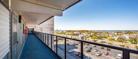 A balcony with a view of a parking lot and buildings.