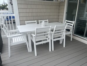 Un patio in legno bianco con tavolo e sedie.