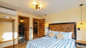 A bedroom with a large bed, wooden headboard, and a ceiling light fixture. - Designer Provenza Flat (Medellín)