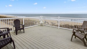 A wooden deck with a white railing overlooking a beach. - Ocean Colony 28 at 47th St.  4 br/ 3 ba, oceanfront townhouse with outdoor pool. (Ocean City)