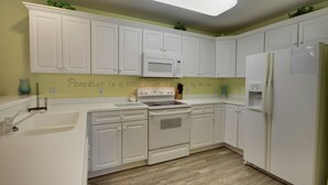 A kitchen with white cabinets, a microwave, a stove, and a refrigerator. - Beautiful condo, located 61st St ocean block. 3 br, with outdoor pool. (Ocean City)