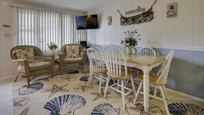 A room with a dining table and chairs, a television, and decorative wall items.